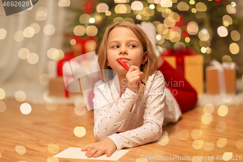 Image of girl writing christmas wish list at home