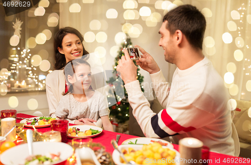 Image of happy family taking picture at christmas dinner