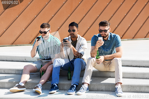 Image of men with smartphones drinking beer on street