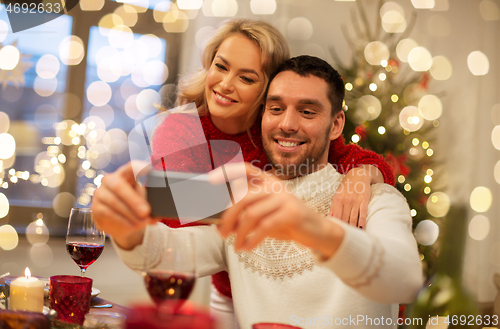 Image of happy couple taking selfie at christmas dinner