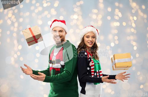 Image of happy couple in sweaters with christmas gifts