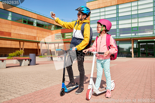 Image of happy school kids with scooters taking selfie