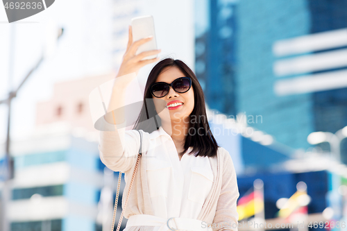 Image of asian woman taking selfie by smartphone in city