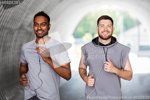 Image of male friends with earphones running outdoors