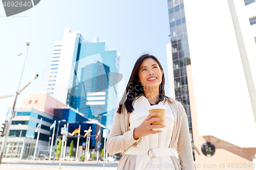 Image of smiling woman with takeaway coffee cup in city