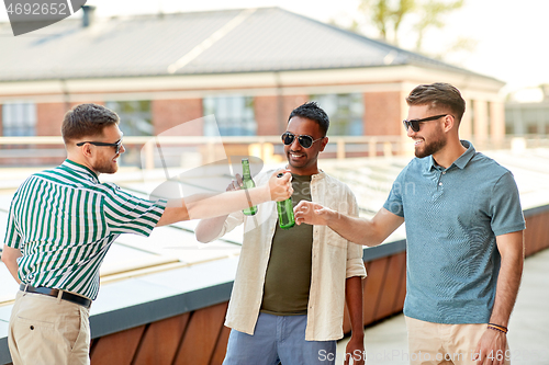 Image of happy male friends drinking beer at rooftop party