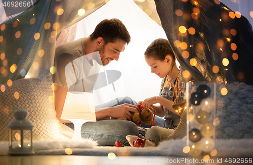 Image of happy family playing with toy in kids tent at home