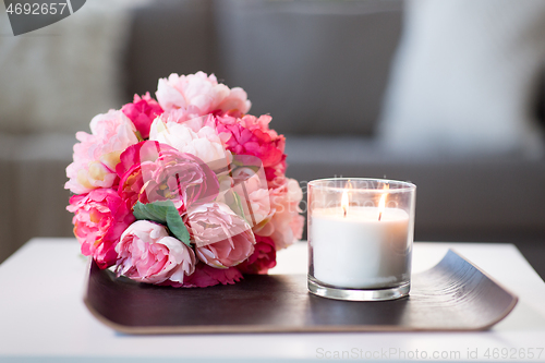 Image of burning fragrance candle and flower bunch at home