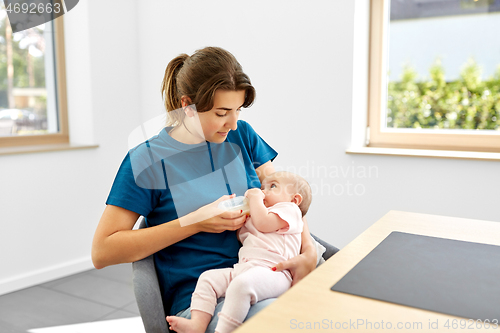 Image of mother feeding baby daughter with milk formula