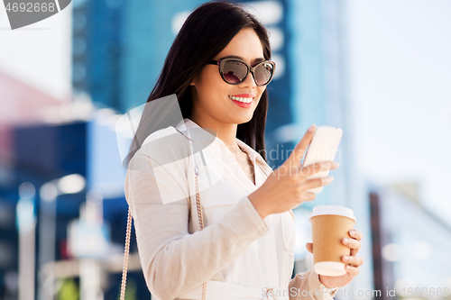 Image of smiling woman with smartphone and coffee in city