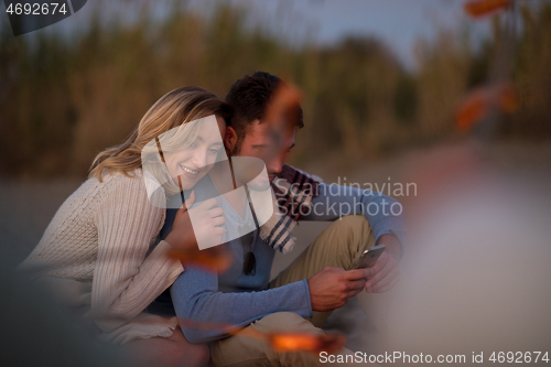 Image of Group Of Young Friends Sitting By The Fire at beach