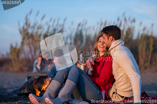 Image of Couple enjoying with friends at sunset on the beach