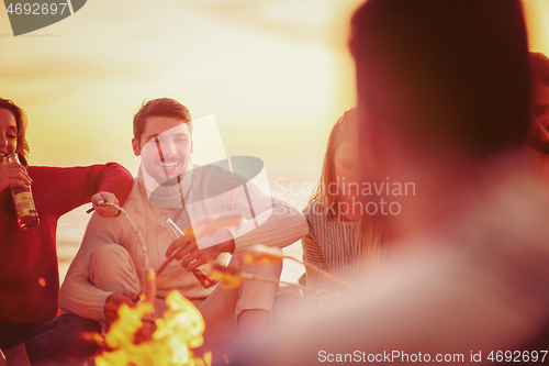 Image of Group Of Young Friends Sitting By The Fire at beach