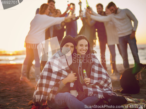 Image of Couple enjoying with friends at sunset on the beach