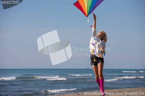 Image of Young Woman with kite at beach on autumn day