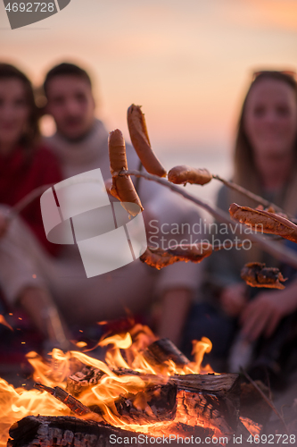 Image of Group Of Young Friends Sitting By The Fire at beach