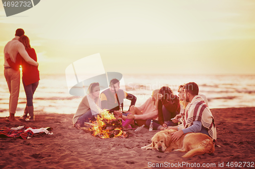 Image of Couple enjoying with friends at sunset on the beach