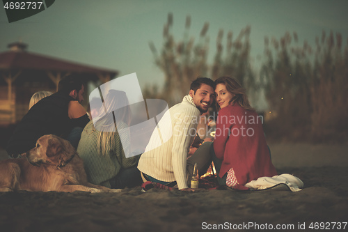 Image of Couple enjoying with friends at sunset on the beach