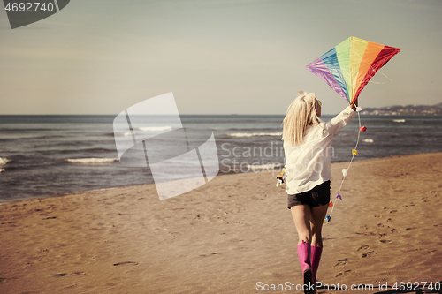 Image of Young Woman with kite at beach on autumn day