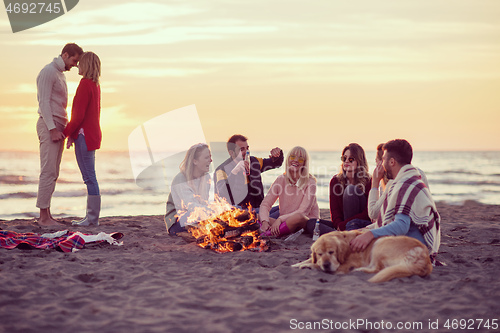 Image of Couple enjoying with friends at sunset on the beach