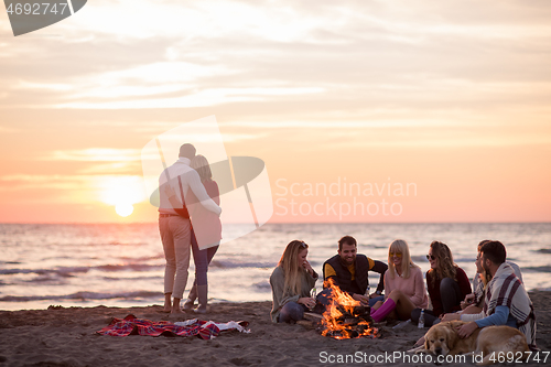 Image of Couple enjoying with friends at sunset on the beach