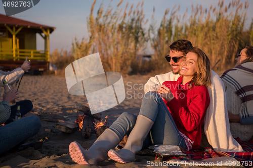 Image of Couple enjoying with friends at sunset on the beach