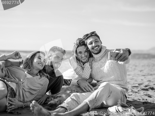 Image of Group of friends having fun on beach during autumn day