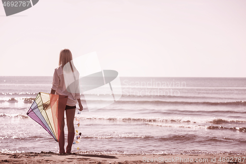 Image of Young Woman with kite at beach on autumn day