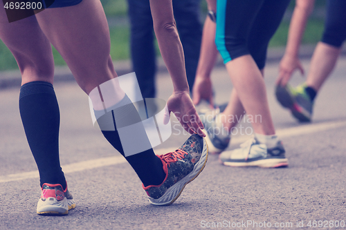 Image of runners team warming up and stretching before morning training