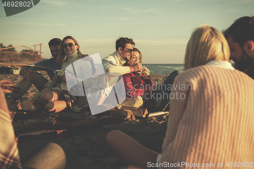 Image of Couple enjoying with friends at sunset on the beach