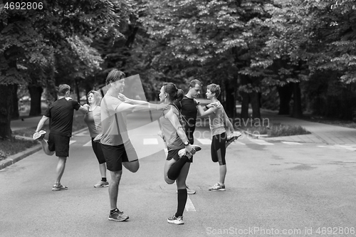 Image of runners team warming up and stretching before morning training