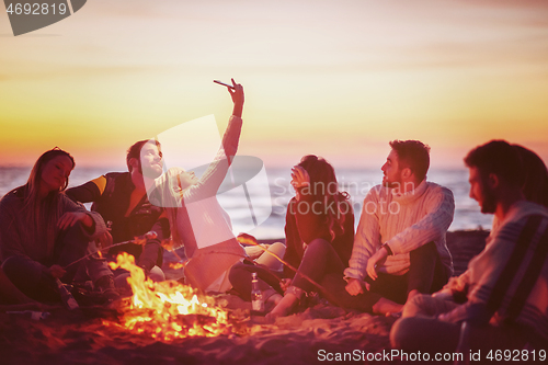 Image of a group of friends enjoying bonfire on beach