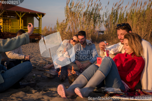 Image of Couple enjoying with friends at sunset on the beach