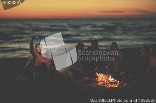 Image of a group of friends enjoying bonfire on beach