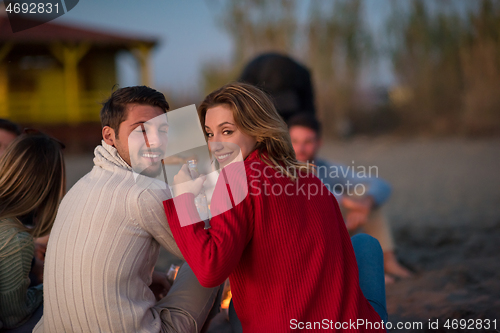 Image of Couple enjoying with friends at sunset on the beach