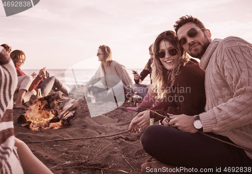 Image of Couple enjoying with friends at sunset on the beach