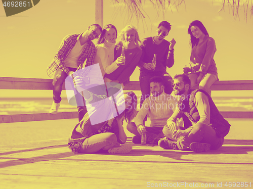 Image of Group of friends having fun on autumn day at beach