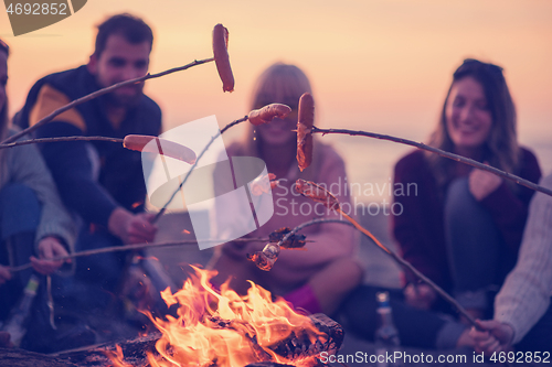 Image of Group Of Young Friends Sitting By The Fire at beach