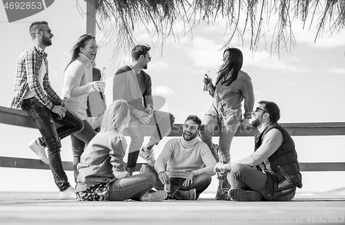 Image of Group of friends having fun on autumn day at beach