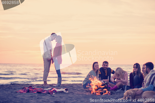 Image of Couple enjoying with friends at sunset on the beach