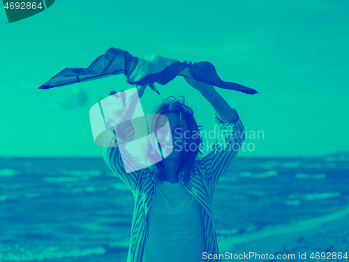 Image of Young Woman holding kite at beach on autumn day