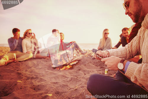 Image of Friends having fun at beach on autumn day