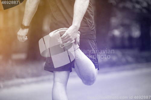 Image of male runner warming up and stretching before morning training