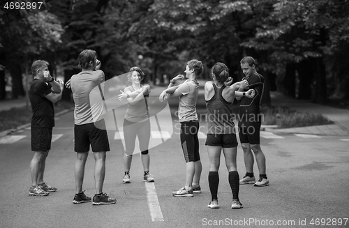 Image of runners team warming up and stretching before morning training