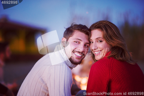 Image of Couple enjoying with friends at sunset on the beach