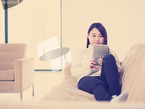 Image of asian woman using Digital Tablet on sofa