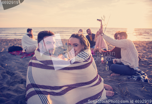 Image of Couple enjoying with friends at sunset on the beach