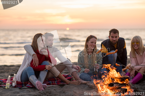 Image of Group Of Young Friends Sitting By The Fire at beach