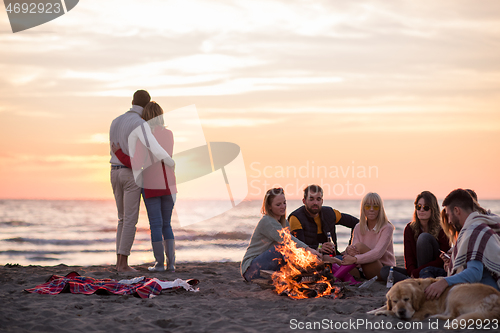 Image of Couple enjoying with friends at sunset on the beach