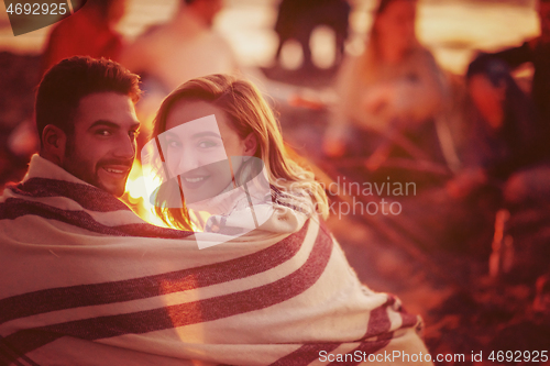 Image of Couple enjoying with friends at sunset on the beach